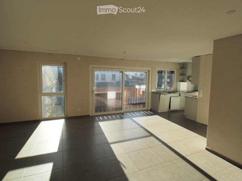 Empty room with tiled floor, large sliding glass doors, and built-in kitchen cabinets.