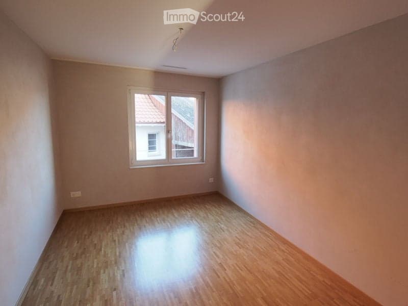Empty room with wooden flooring and a single window, no furniture or equipment.