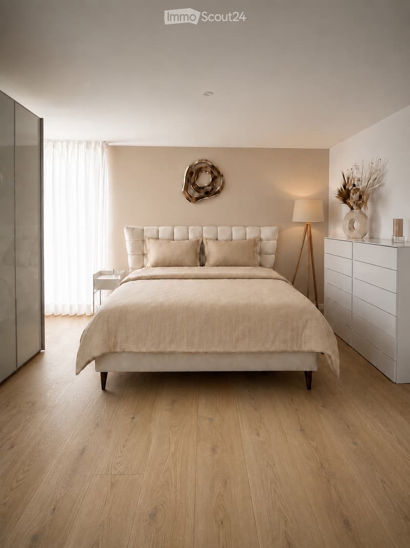 Modern bedroom with a large bed, beige bedding, wooden floor, nightstand, mirror, floor lamp, and decorative wall art.