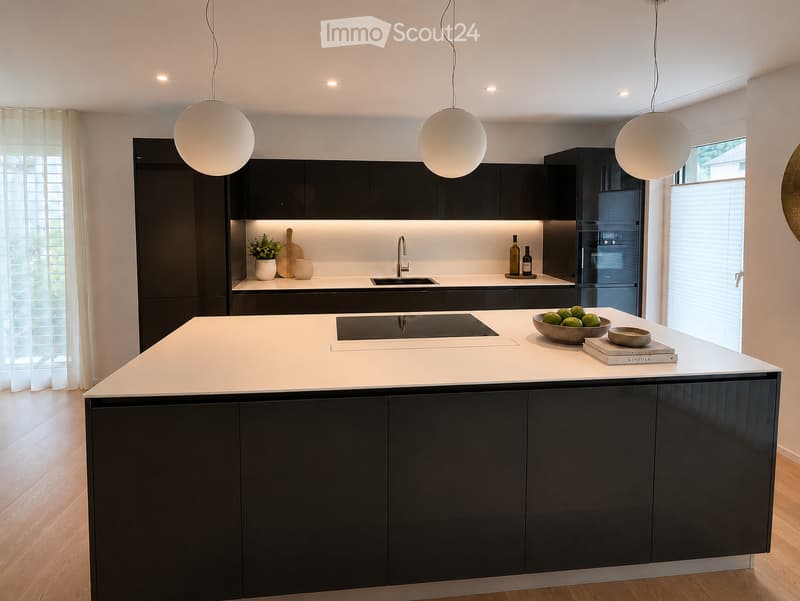 Modern kitchen with black cabinetry, white countertops, pendant lights, and a central island with a built-in induction cooktop. Includes a sink, bowl of fruit, books, and a potted plant on the counter.