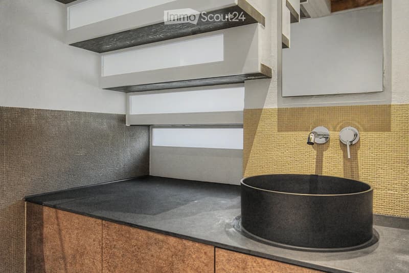 Modern bathroom with a sleek black sink, chrome faucet, and contemporary cabinetry.