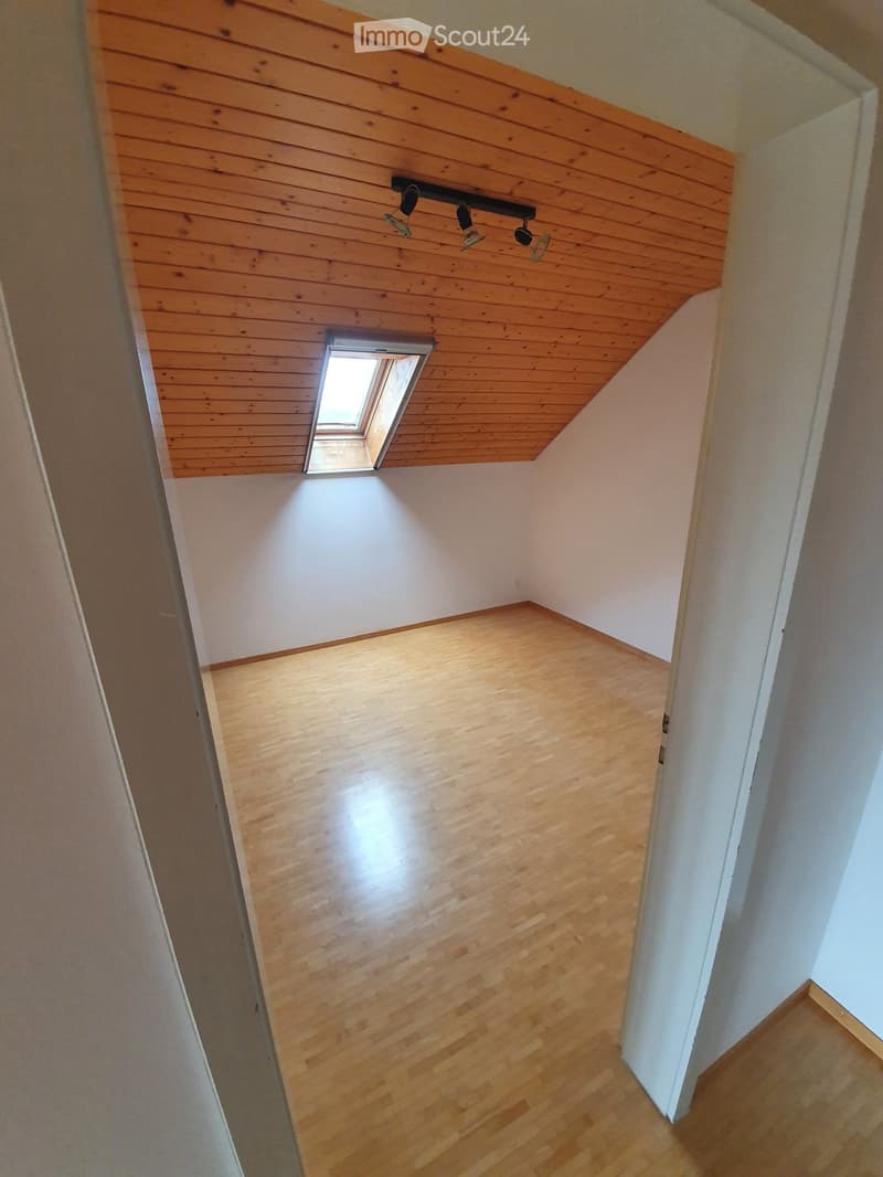 Empty room with wooden flooring and white walls, featuring a skylight window and recessed lighting fixture on the ceiling.