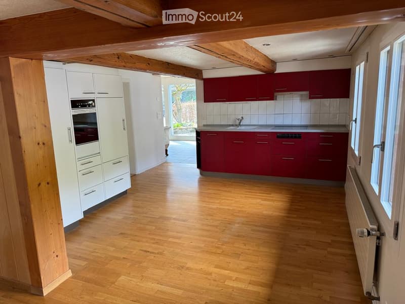 Modern kitchen with white and red cabinets, wooden flooring, and stainless steel appliances including an oven and sink.