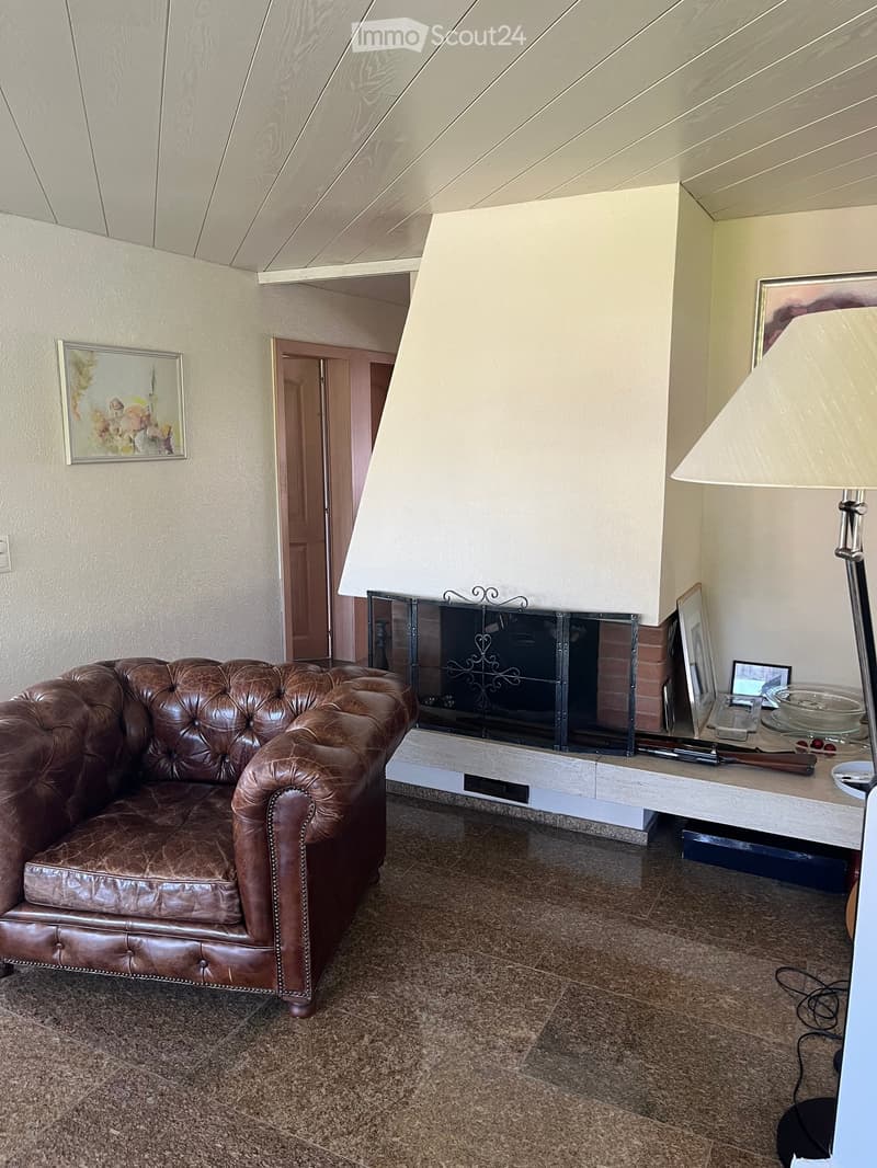 Fireplace, brown leather armchair, marble floor, white walls, white ceiling, window, paintings on the wall