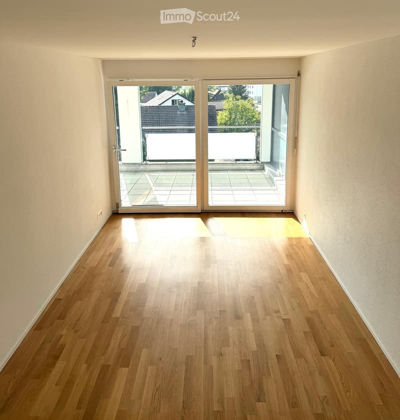 Empty room with wooden flooring and large sliding glass doors leading to a balcony or terrace area.