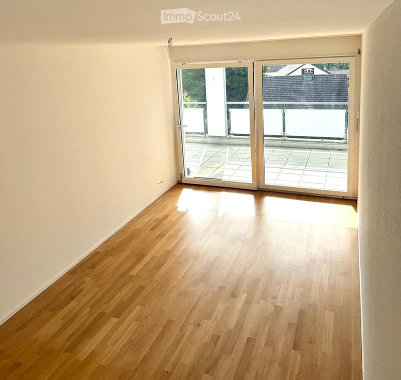 Empty room with wooden flooring and large sliding glass doors leading to a balcony or terrace area.