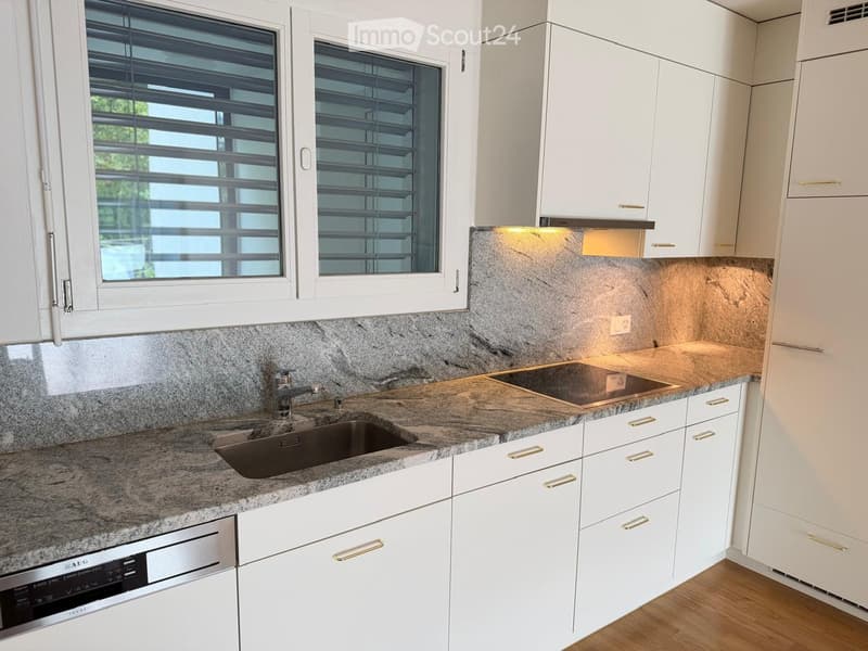 Modern kitchen with white cabinets, granite countertops, a sink, a dishwasher, and a stove. The backsplash is made of marble tiles, and the windows have blinds.