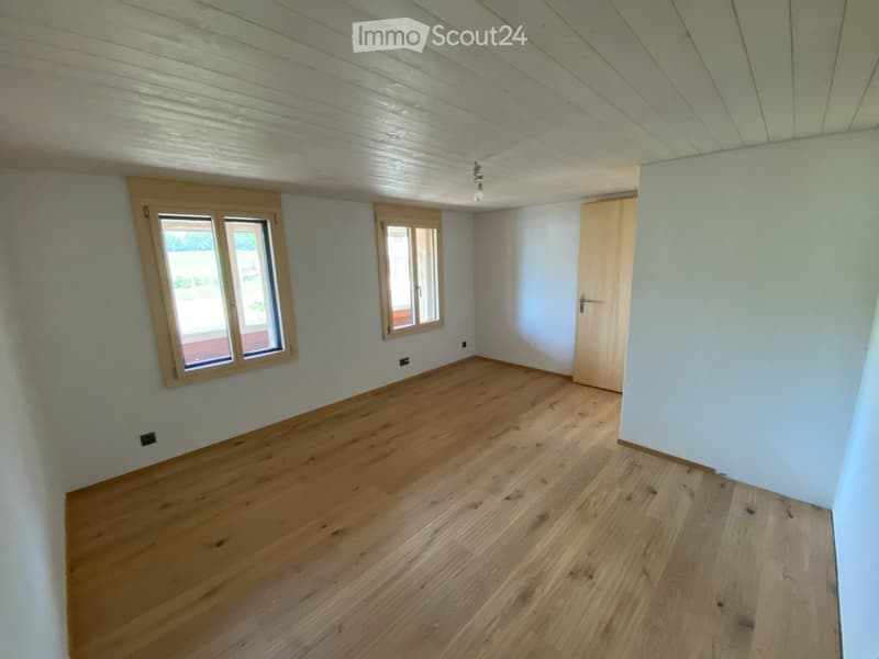 Empty room with wooden flooring, white walls, and large windows. No furniture or equipment present.