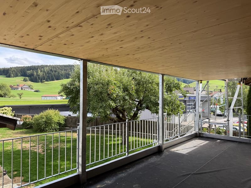 Balcony with wooden ceiling, metal railing, and scenic countryside view.