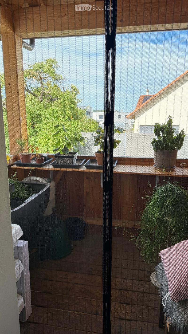 Wooden balcony with potted plants, a sink, and a cushioned seat.