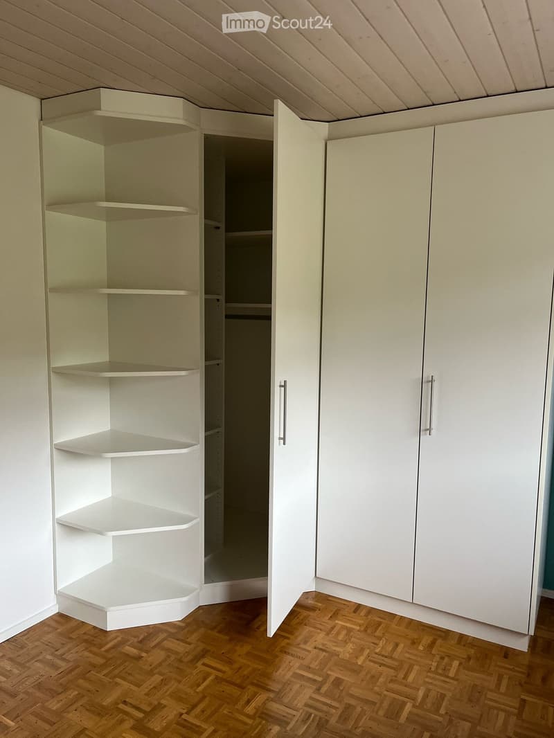Large corner wardrobe with shelves and double doors. Wood floor.