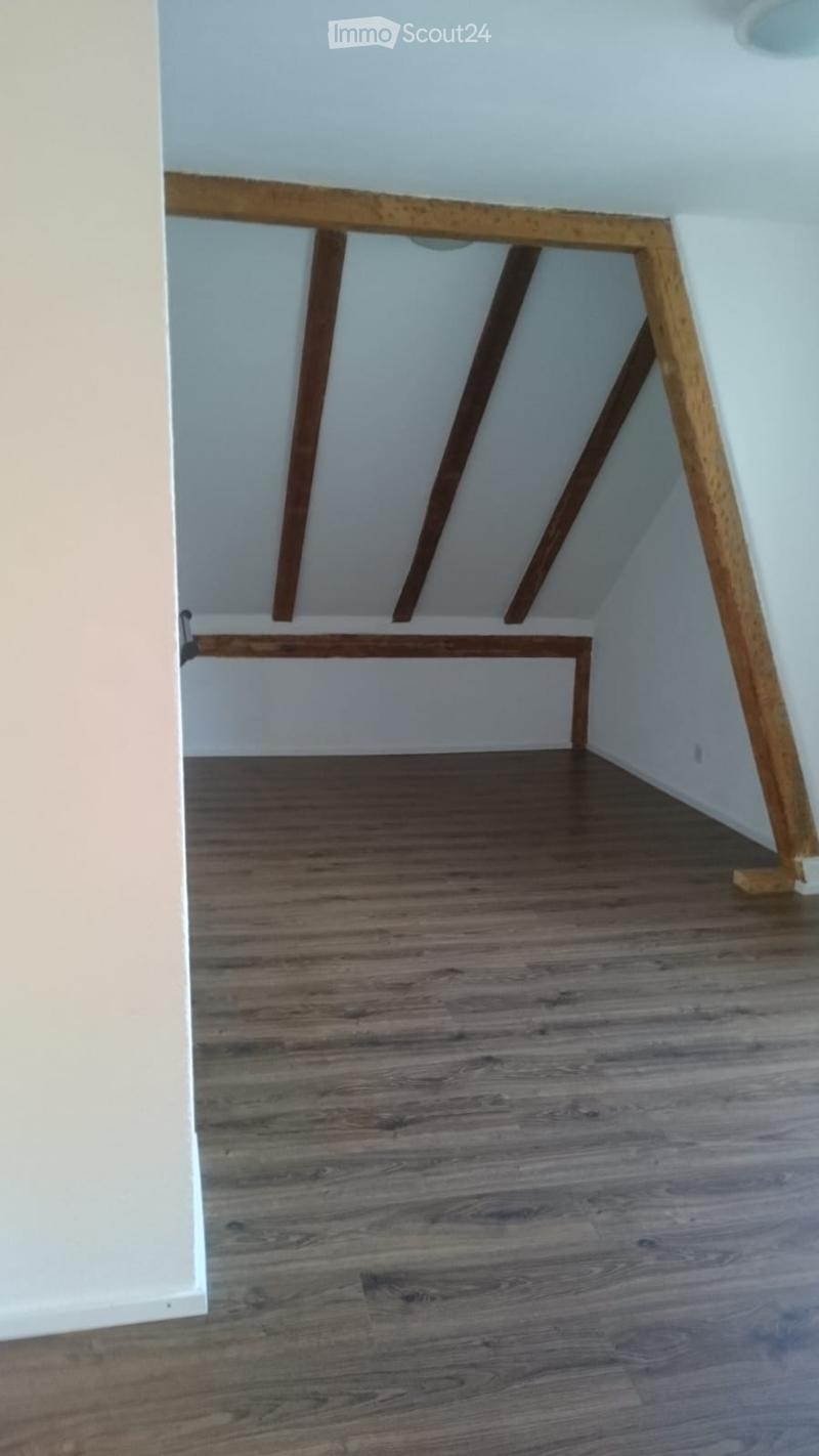 Empty attic space with wooden flooring and exposed wooden beams on the ceiling. No furniture or equipment present.