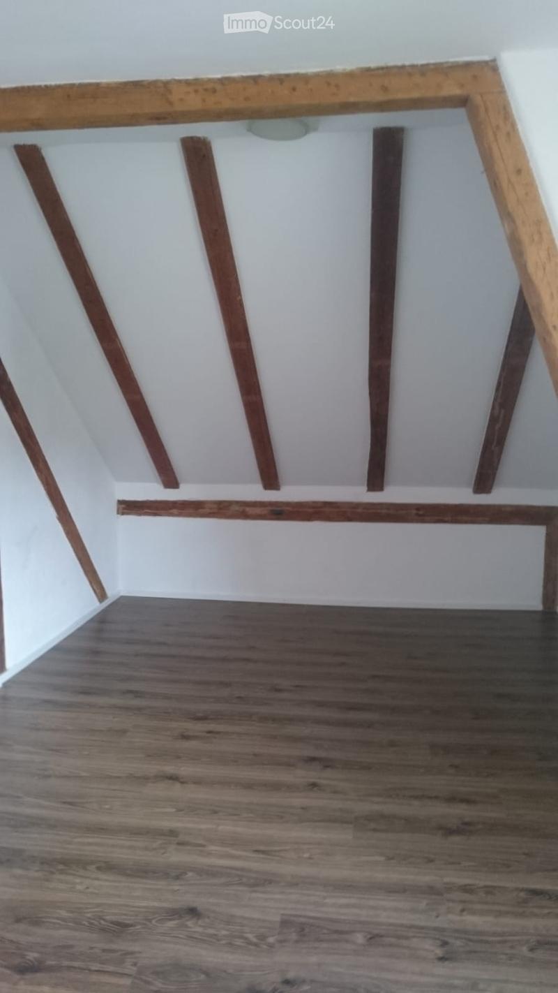 Empty room with wooden flooring and exposed wooden beams on the ceiling. No furniture or equipment present.