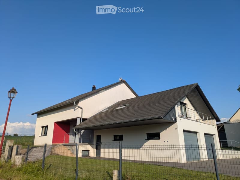 Modern two-story house with white and red exterior, dark roof, garage, and fenced front yard.