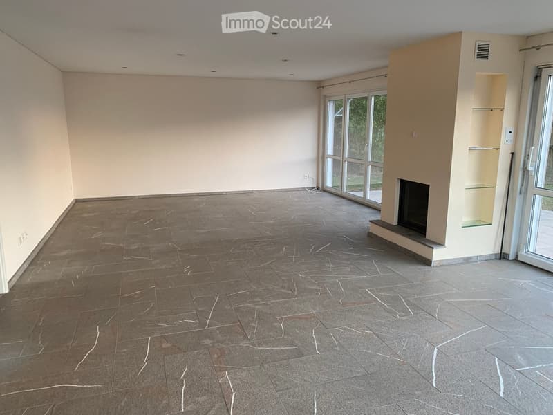 Empty room with tiled floor, white walls, large windows, and a fireplace.