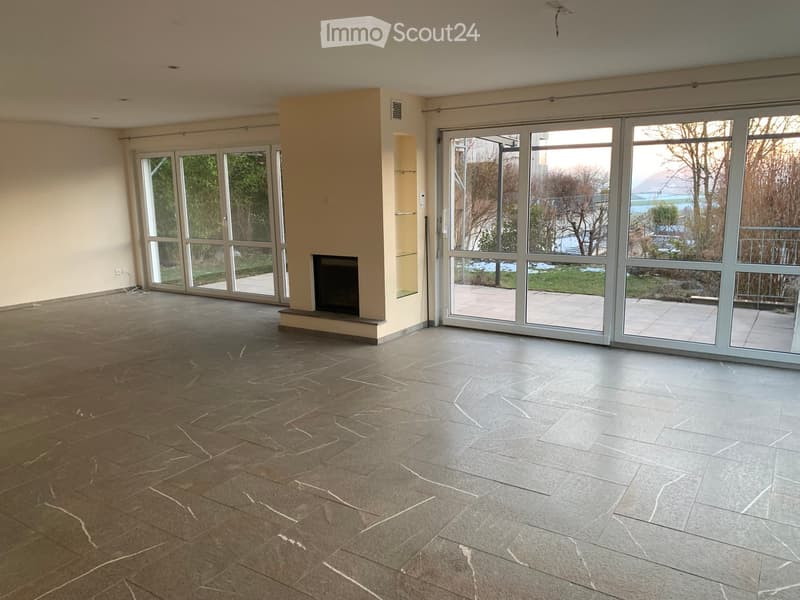 Empty room with large glass sliding doors, fireplace, and tiled floor.