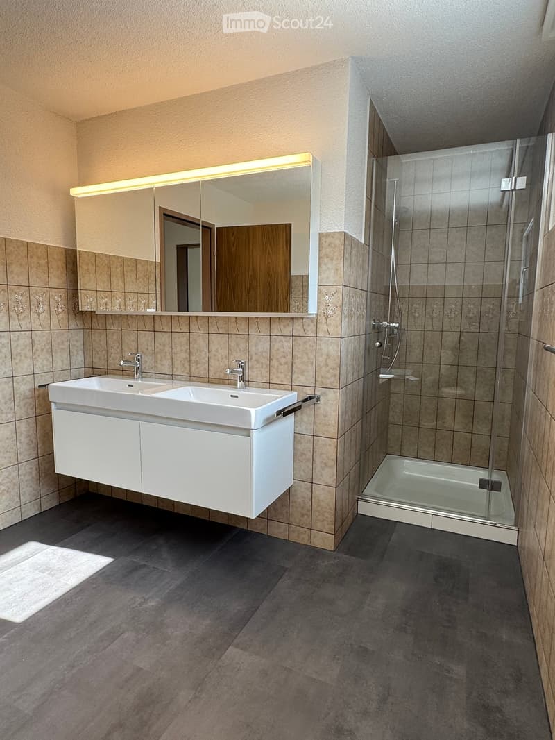 Dual sinks, large mirror, shower, tiled floor, modern fixtures