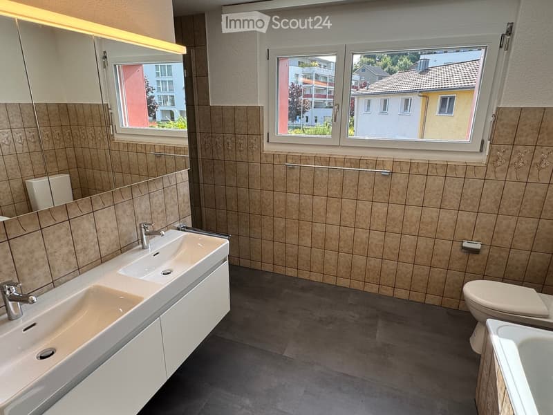 Bathroom with two sinks, a bathtub, a toilet, a mirror, and two windows