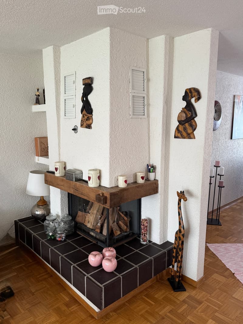 Living room with a central fireplace, wooden mantel, and various decorative items including a giraffe figurine, candles, and vases.