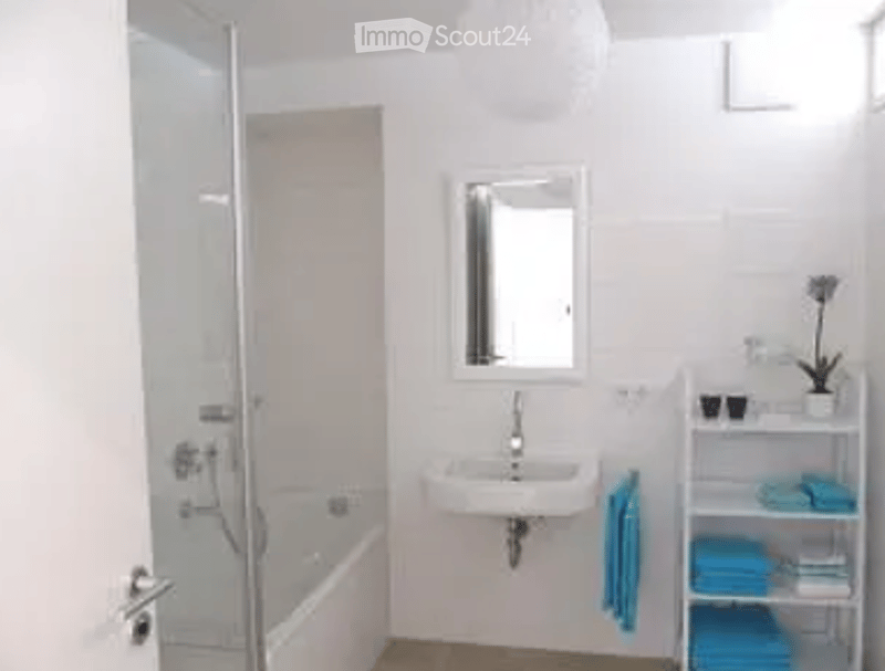 Modern bathroom with a bathtub, sink, mirror, and towel rack with neatly folded towels.
