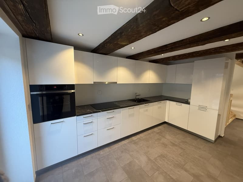 Modern kitchen with white cabinets, stainless steel appliances, and a dark countertop.