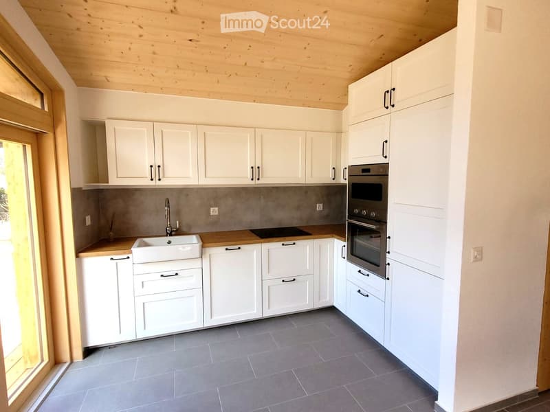 Modern kitchen with white cabinets, wooden countertops, stainless steel appliances, and a sink with a faucet.