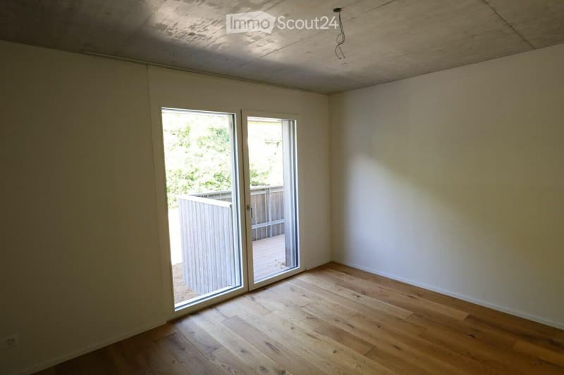 Empty room with wooden flooring and large sliding glass doors leading to an outdoor deck.