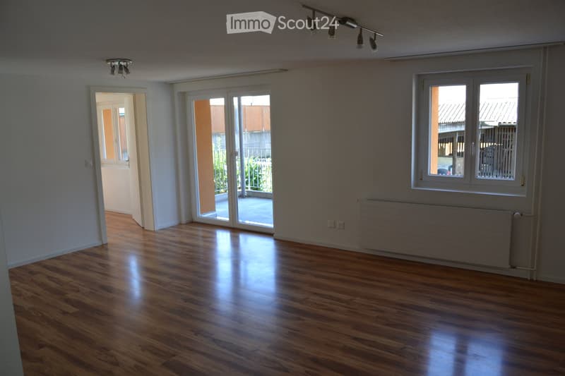 Empty room with wooden flooring, large sliding glass doors, and white walls. No furniture or equipment present.