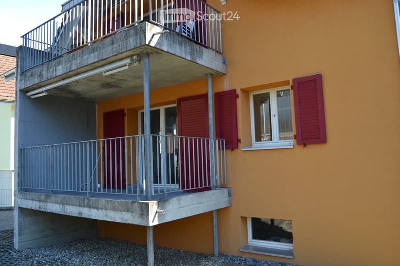Two-story building with orange exterior, red shutters, and multiple balconies with metal railings.