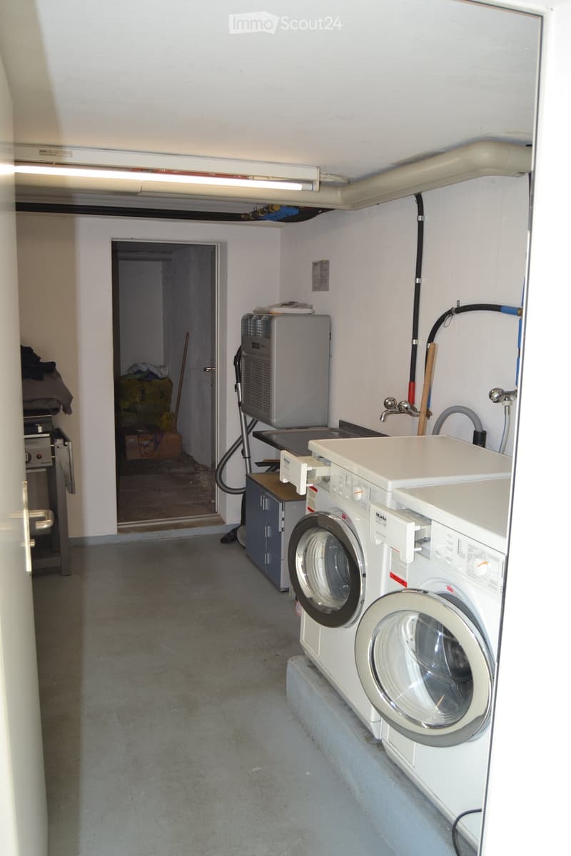 Utility room with a washing machine, dishwasher, and a small sink with a faucet. There is a cabinet and a door leading to another area.