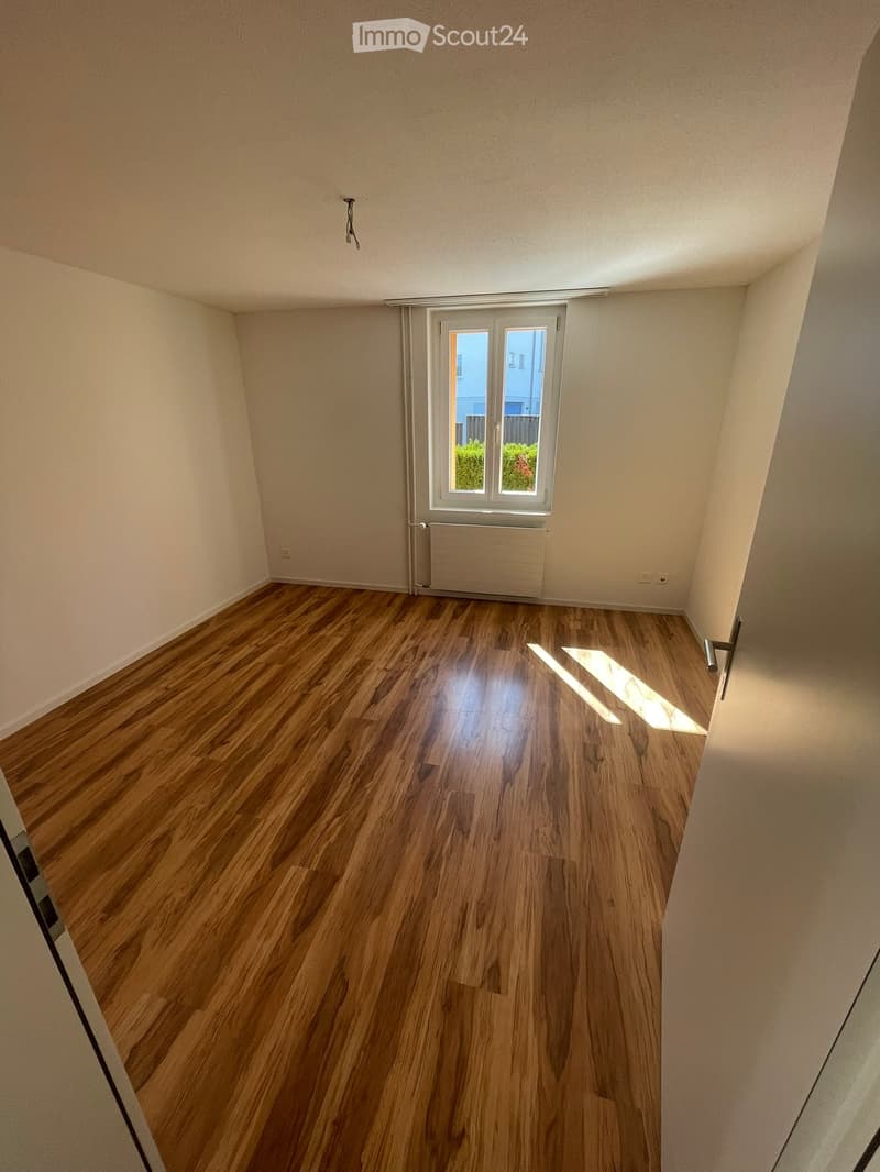Empty room with wooden flooring, white walls, and a window with blinds. No furniture or equipment is present.