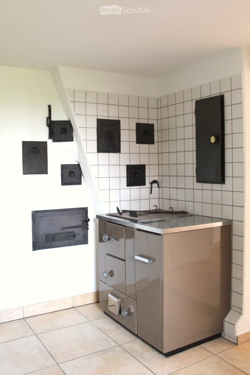 Modern kitchen with stainless steel stove, tiled walls, and built-in cabinets.