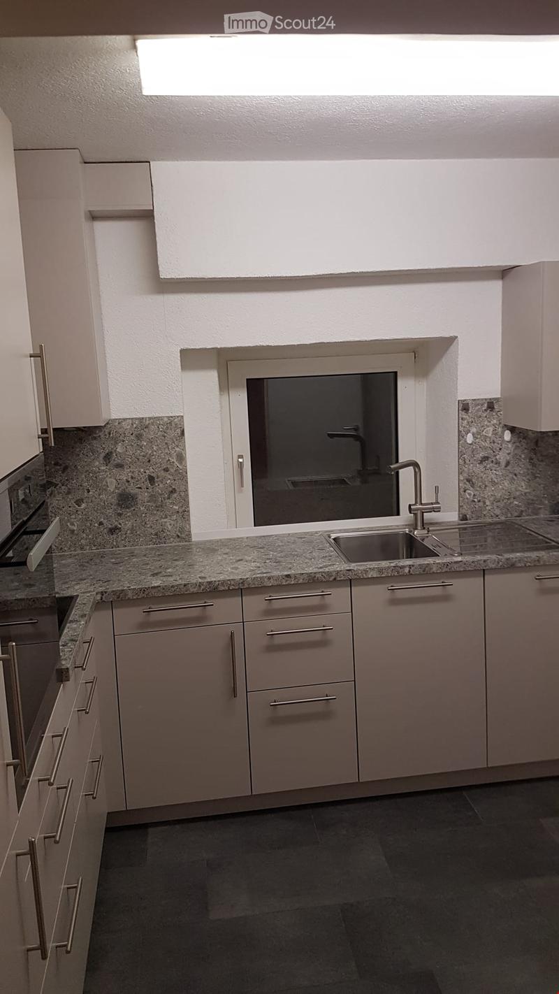 Modern kitchen with light grey cabinets, granite countertop, and stainless steel sink and faucet.