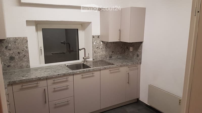 Modern kitchen with granite countertops, white cabinets, and a stainless steel sink.