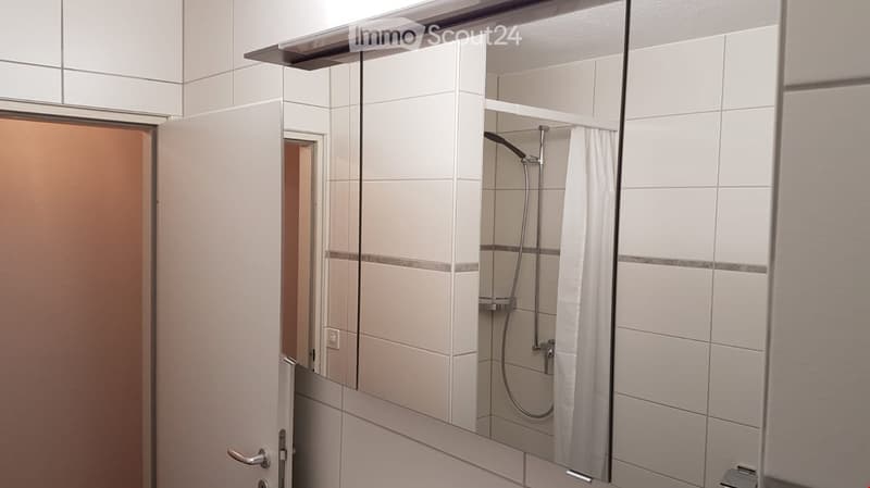 Modern bathroom with white tiled walls, a glass-enclosed shower area, and a shower curtain.
