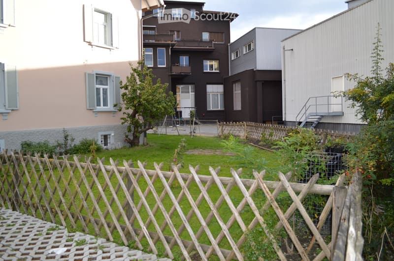 A garden with a wooden fence in front of the building.
