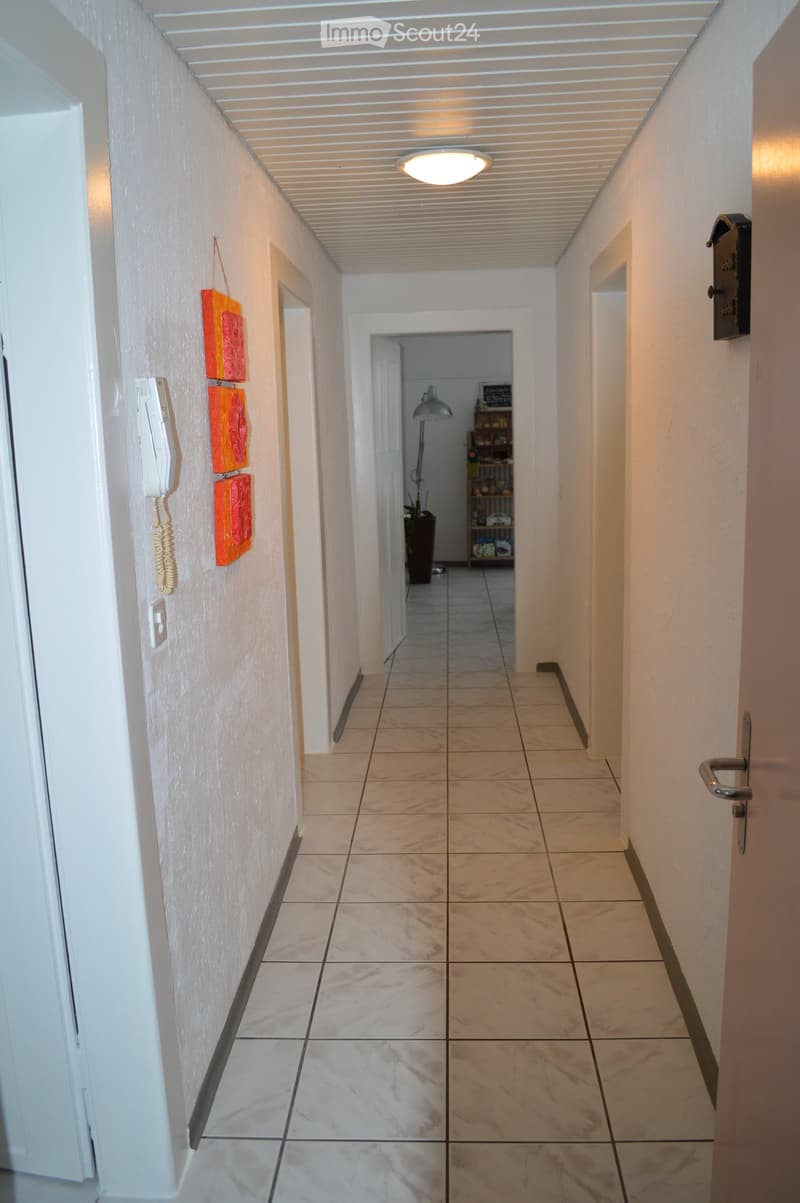 White tiled floor, white walls, lamp, telephone, 3 doors, 2 rooms, painting, plant