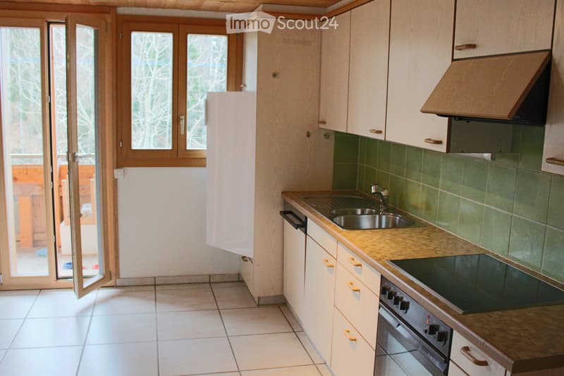 Kitchen. Modern kitchen with light-colored cabinets, a stainless steel sink, and a built-in oven. Green tiled backsplash and wooden countertop.