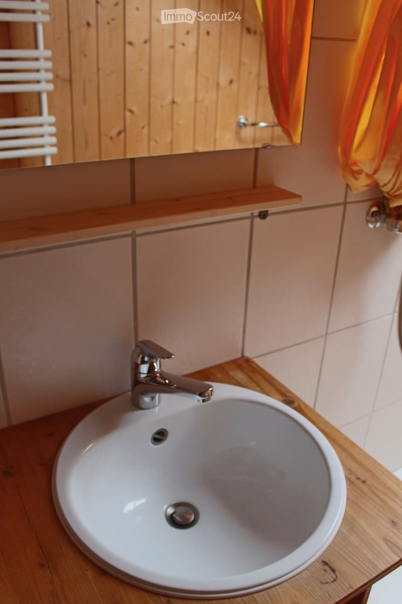 Bathroom. Bathroom with a white sink, chrome faucet, wooden countertop, and a mirror with an orange curtain.