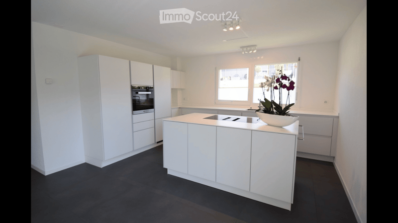 Modern kitchen with white cabinets, central island, and dark flooring.