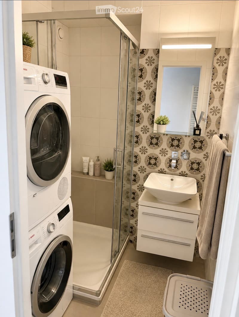 Modern bathroom with a washing machine, sink, mirror, shower, and decorative plants.