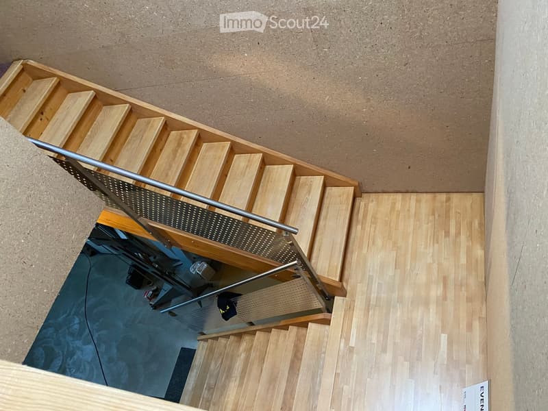 Wooden staircase with metal railing, leading to a lower level with visible equipment and a blue surface.