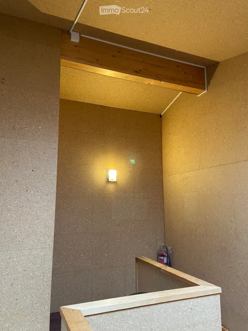 Modern hallway with wooden railings, concrete walls, and recessed lighting.