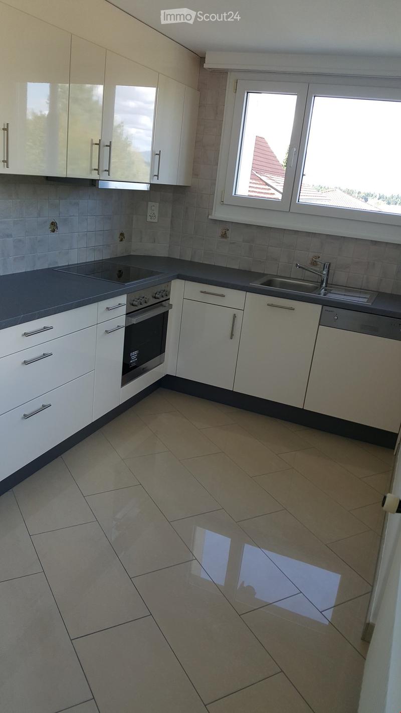 Modern kitchen with white cabinets, stainless steel appliances, and tiled flooring.
