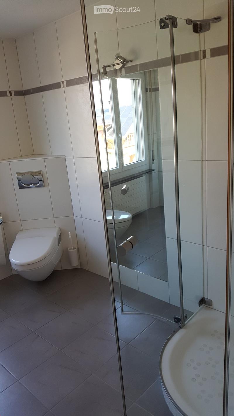 Modern bathroom with a glass-enclosed shower, toilet, bathtub, and tiled walls and floor.