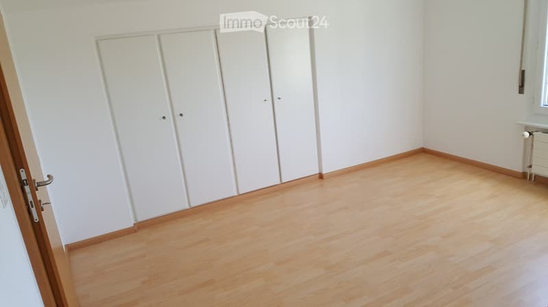 Empty room with light wooden flooring, white walls, and built-in white wardrobes. No furniture or personal items are present.