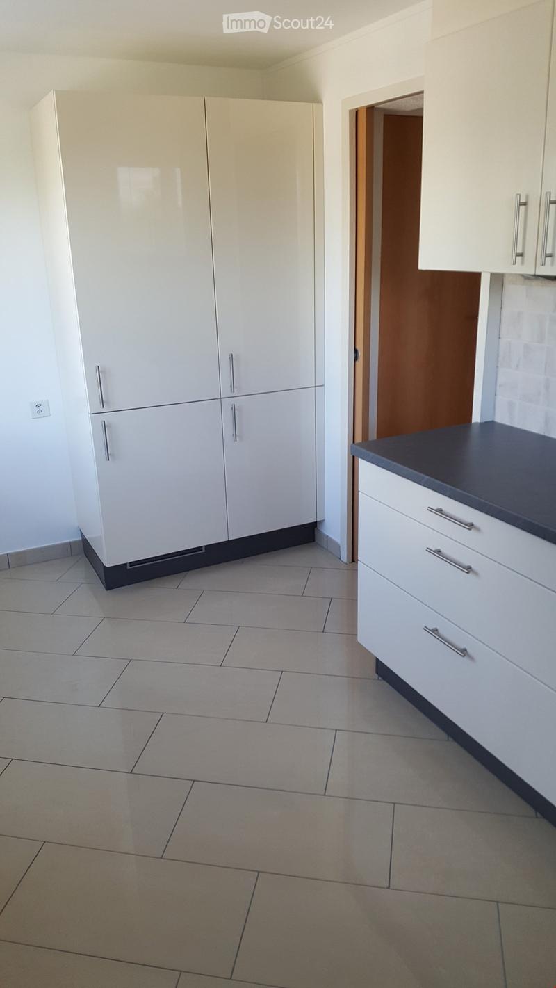 Empty kitchen with white cabinets, tiled floor, and a dark countertop. No appliances or furniture are present.