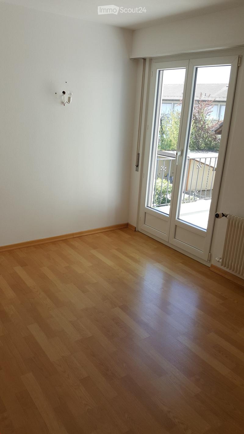 Empty room with wooden flooring, white walls, and a large sliding glass door leading to a balcony.