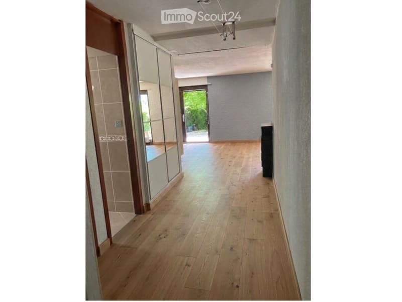 Empty hallway with wooden flooring, light-colored walls, and a glass door leading to an outdoor area.