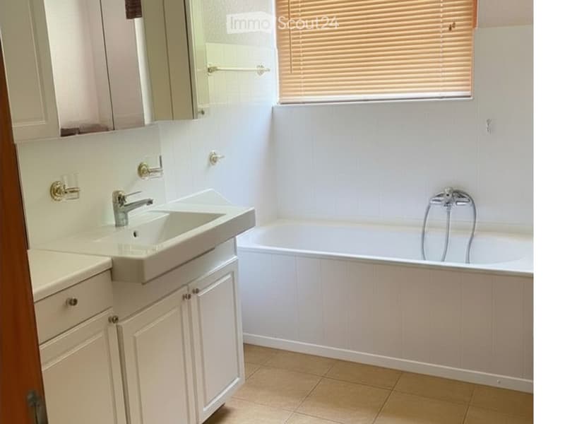 Bathroom with a white sink, bathtub, and light-colored cabinets.